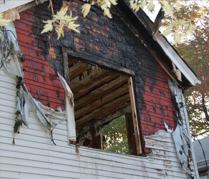 fire damaged home with melted siding and broken glassfire damaged home with melted siding and broken glass