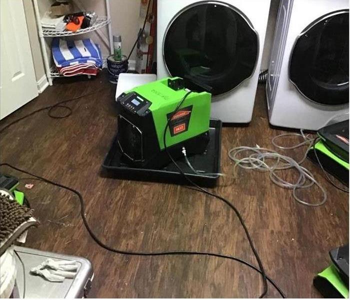 Machines drying water damage in a laundry room