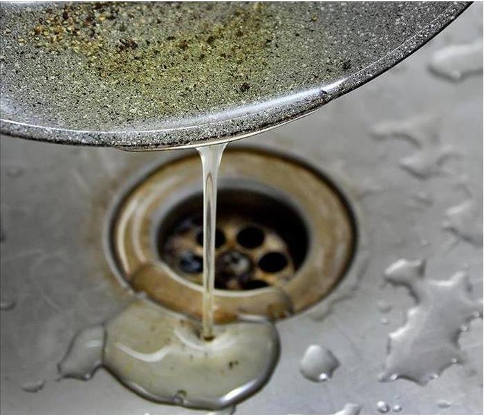 Grease is shown being poured into a drain in a sink