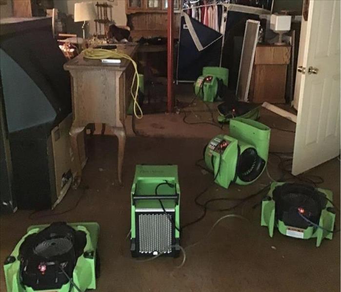 Green restoration equipment is shown in a flooded basement 