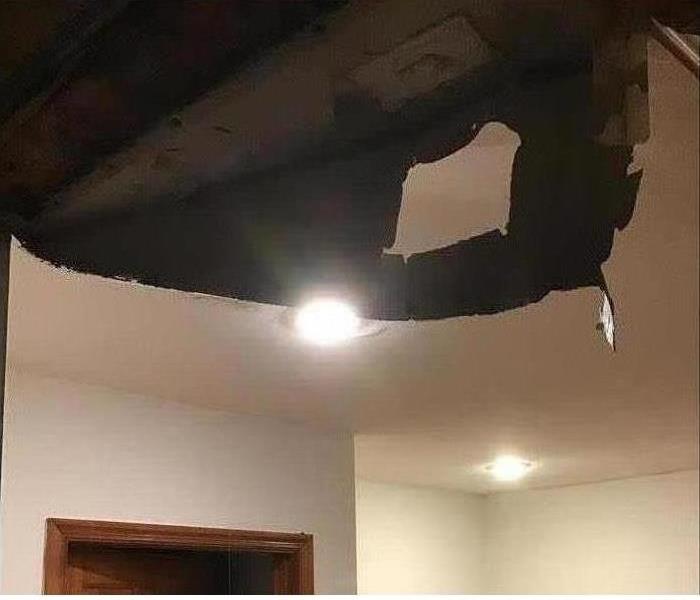A water damaged ceiling is shown partially collapsing